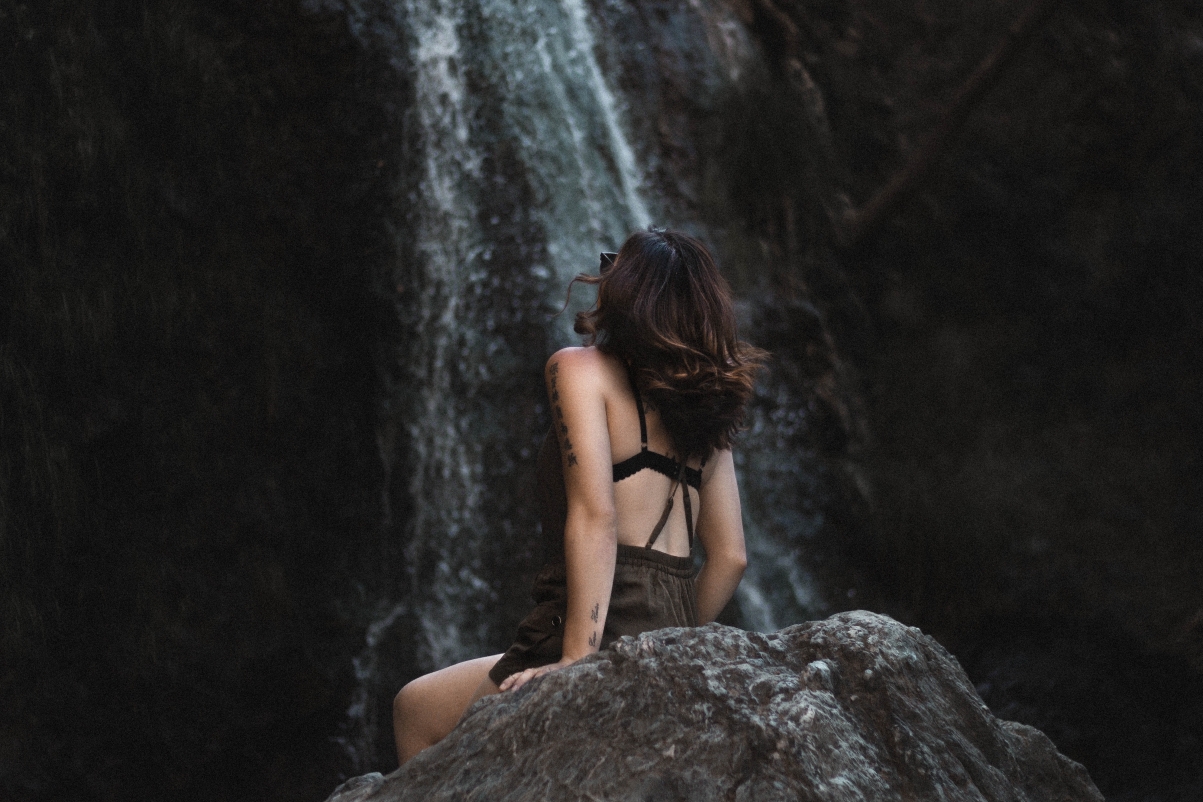 坐在岩石上观望瀑布的美女5K壁纸