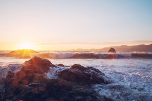 夕阳下的礁石海浪海报背景